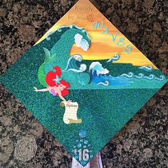 a child's graduation cap decorated with an image of the little mermaid on it