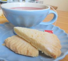 two pieces of bread on a blue plate next to a cup of tea