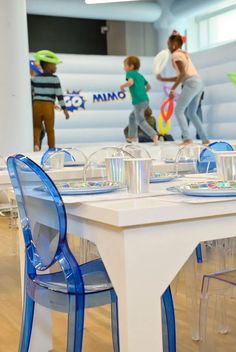 the children are playing with their tennis rackets at the indoor table set for two