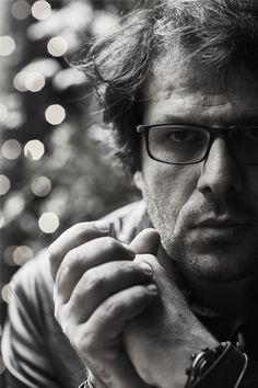 black and white photograph of a man with glasses holding his hand up to his face