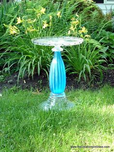 a blue glass bird bath sitting in the grass