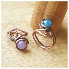 two rings sitting on top of a wooden table next to a piece of wood and some wire