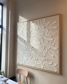 a large white artwork hanging on the wall next to a chair in a dining room