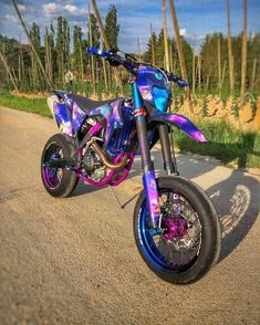 a purple and blue motorcycle parked on the side of a road