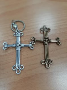 two metal crosses sitting on top of a wooden table