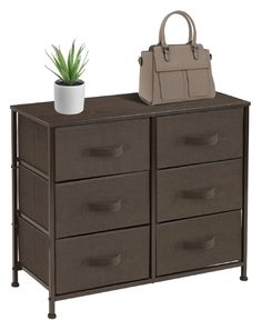 a black dresser with drawers and a purse on top, next to a potted plant