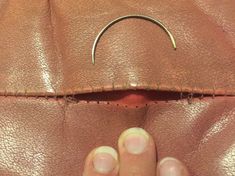 a person holding onto a brown purse with a metal ring on the inside of it