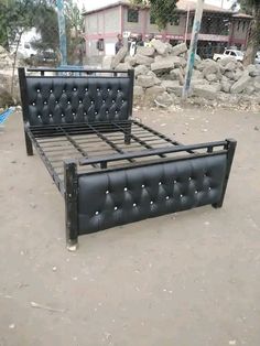 a black bed frame sitting on top of a dirt ground