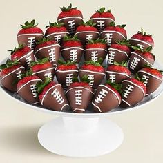 chocolate covered strawberries are arranged on a cake plate with footballs and strawberries