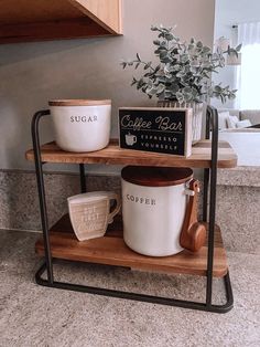 two coffee mugs are sitting on a wooden shelf next to a potted plant