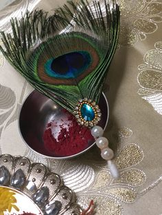 a peacock feather resting on top of a metal bowl