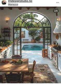 a kitchen with an arched glass door leading to the swimming pool and outdoor dining area