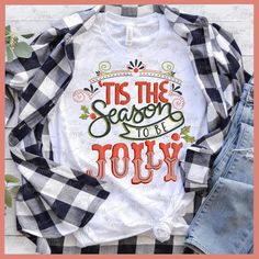 a t - shirt that says tis the season to be jolly with plaid sleeves and jeans