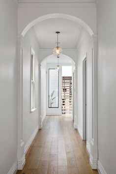 an empty hallway with white walls and wood floors