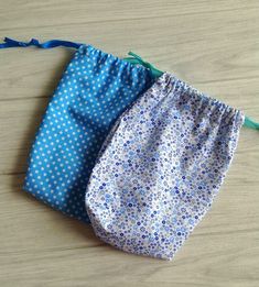 two blue and white bags sitting on top of a wooden table next to each other