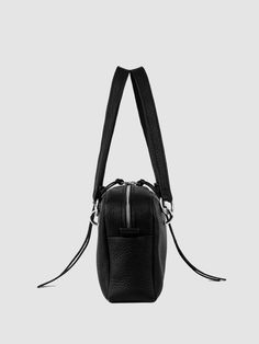 A stunning blend of past and present fashion trends, the JAMIE bowling bag exudes a captivatingly dark and edgy design. Crafted from supple pebbled black leather, it features piercing-like handle attachments, pull tabs, organic cotton twill lining, and twin-headed zippers with tassel pulls. With dimensions of L11.5 x H6.5 x W3" and a strap drop of 9", this bag is the perfect balance of sophistication and nostalgia. Black Textured Leather Bag With Round Handle, Modern Black Textured Leather Satchel, Black Satchel With Round Handle For Travel, Modern Leather Camera Bag With Gunmetal Hardware, Modern Black Satchel With Round Handle, Everyday Black Satchel With Round Handle, Black Textured Leather Satchel For On-the-go, Black Textured Leather Satchel, Top Handle Satchel With Gunmetal Hardware