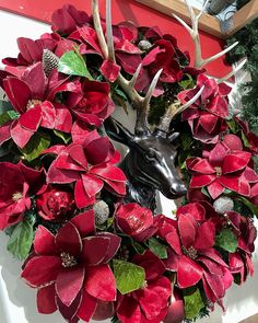 a wreath with red poinsettis and antlers is hanging on the wall