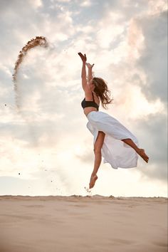 a woman jumping in the air while wearing a white dress