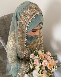 a woman in a wedding dress holding a bouquet of flowers and wearing a headscarf