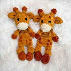 two crocheted giraffes sitting next to each other on a white blanket