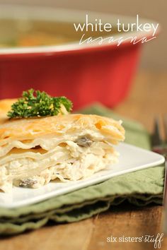 a white plate topped with lasagna next to a red bowl filled with broccoli