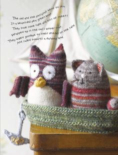 two knitted stuffed animals sitting in a basket on a table next to a globe