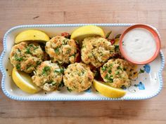 crab cakes with lemon wedges on a plate next to a small bowl of ranch dressing