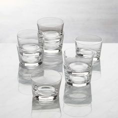 four clear glass cups sitting on top of a white table next to eachother