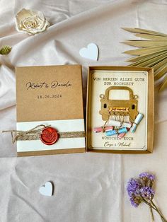 an open box on a bed with some flowers and other items in it next to a flower