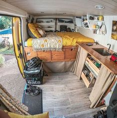 the interior of a camper van with bed, desk and storage area in it