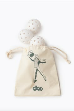 three white balls are in a drawstring bag on a white surface, with the word docc printed on it