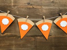 an orange and white paper banner with clouds on it hanging from a string against a wooden wall