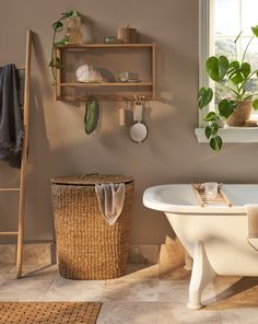 a bath tub sitting next to a window and a shelf filled with potted plants