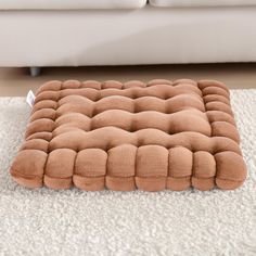 a brown square cushion sitting on top of a white rug