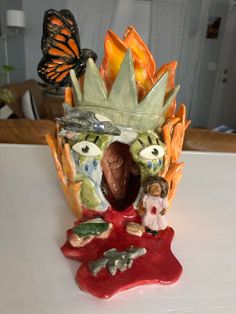 a figurine that is on top of a white table next to a butterfly