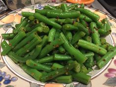 a plate with green beans and seasonings on it, sitting on a floral table cloth