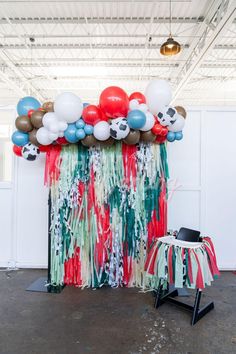 a table with balloons and streamers on it in front of a backdrop that looks like soccer balls