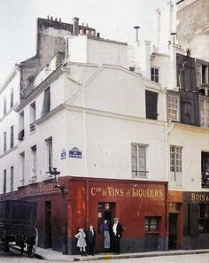 an old photo of people standing in front of a building on the corner of a street