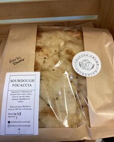 some kind of food wrapped in plastic on top of a wooden box with a label that says sourdoudough focaccia