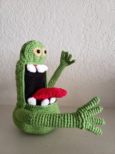 a crocheted green toy sitting on top of a white table next to a wall