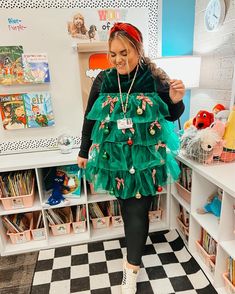 a woman in a green dress standing next to a book shelf filled with children's books