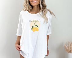 "Add a zesty twist to your wardrobe with our \"Limoncello\" t-shirt, capturing the refreshing essence of this vibrant Italian classic. This comfortable tee is the perfect blend of style and comfort, inviting you to savor the simple pleasures of life. .: 100% Airlume combed and ringspun cotton (fiber content may vary for different colors) .: Light fabric (4.2 oz/yd² (142 g/m .: Retail fit .: Tear away label .: Runs true to size" White Crew Neck T-shirt With Lemon Print, Casual Lemon Tops For Summer, Casual Crew Neck Top With Lemon Print, White Short Sleeve Top With Lemon Print, White Lemon Print T-shirt For Summer, White Short Sleeve T-shirt With Lemon Print, Spring Lemon Print Short Sleeve Tops, Casual Relaxed Fit Lemon Print Tops, Casual Relaxed Fit Top With Lemon Print