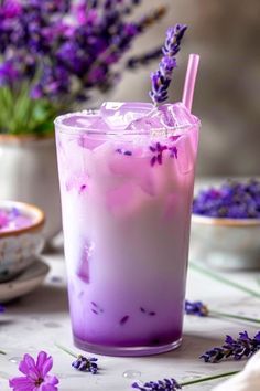 a purple drink sitting on top of a table next to some lavender flowers and plates