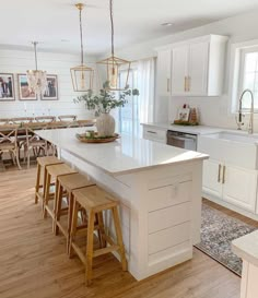 a kitchen with white cabinets and wooden stools next to an island in the middle