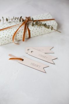 two tags tied together with twine on top of a white tablecloth next to a gift bag