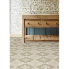 a wooden table with two drawers in front of a white brick wall and flooring