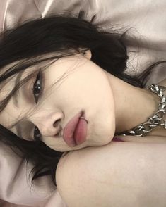 a woman laying on top of a bed with her tongue hanging out and eyes closed