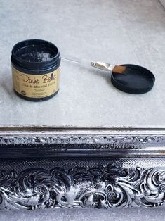 a paint can and brush sitting on top of a silver frame next to a mirror