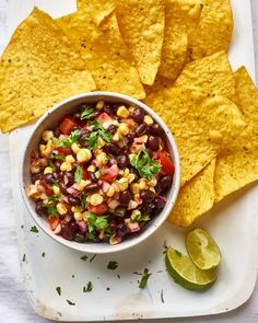 a white plate topped with corn and black bean salsa next to tortilla chips