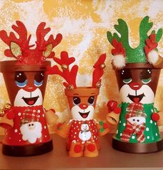 three christmas themed vases are sitting on a table with snowmen and reindeer decorations